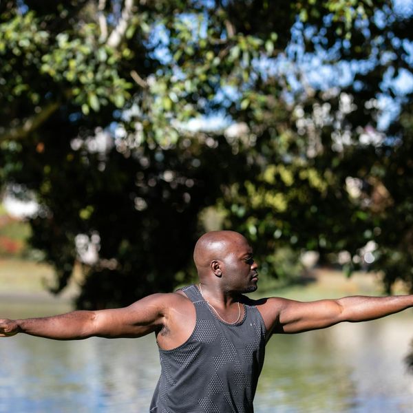 Person stretching gently outdoors with the sun in the background.